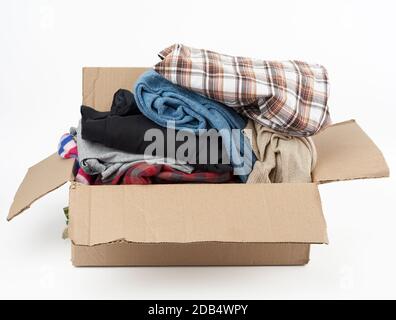 big brown cardboard box filled with various clothes on a white background, donation concept Stock Photo