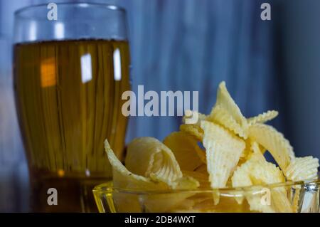 Cold beer and wavy potato chips in a bowl on a wood table - empty copy space area Stock Photo