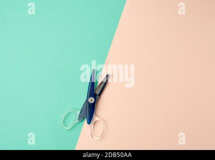 blue plastic paper scissors on a green-beige background, top view, flat lay Stock Photo