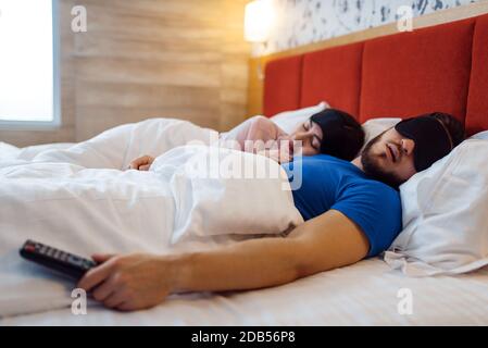 Love couple sleeping in eye covers in bed at home, healthy comfort sleep. Harmonious relationship in young family. Man and woman resting together in t Stock Photo