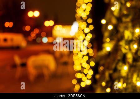 Cozy evening in the festive city. Blurred image of trees decorated with light garlands for Christmas and New Year celebration time. Shining trees Stock Photo