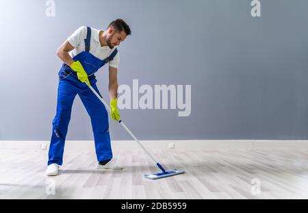 Worker Mopping Floor With Mop In Office Stock Photo
