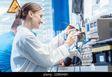 Team of engineers, woman and man, testing and measuring an electronic product in the lab together Stock Photo