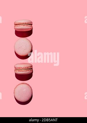 Pink macarons with copy space. Row of perfect french macarons or macaroons on pink background. Top view or flat lay. Hard light Stock Photo