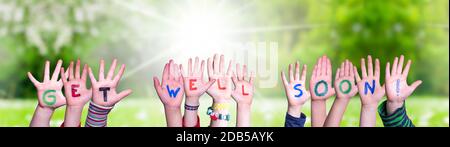 Children Hands Building Colorful English Word Get Well Soon. Sunny Green Grass Meadow As Background Stock Photo