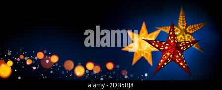 Ornate red and gold star lanterns for Christmas on dark blue and black background, extra wide format with copy space Stock Photo