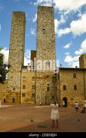 Torri dei Salvucci, medieval twin towers in the old town of San Gimignano, Unesco World Heritage Site, with tourists in summer, Siena, Tuscany, Italy Stock Photo