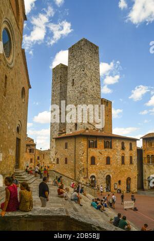 People and tourists on the staircase of the Duomo with the Torri dei Salvucci twin towers in the medieval town of San Gimignano, Siena, Tuscany, Italy Stock Photo