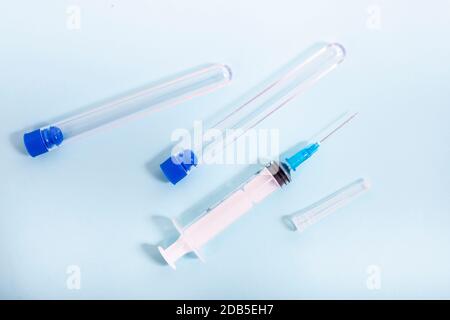 syringe and testing vials over a light blue background. Stock Photo