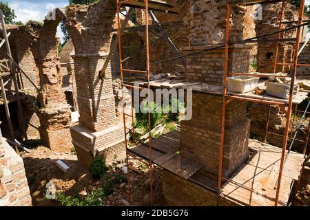 old brickwork of different bricks and ruined and dilapidated arches, is part of the old castle, the restoration of the fortress, scaffolding installed Stock Photo