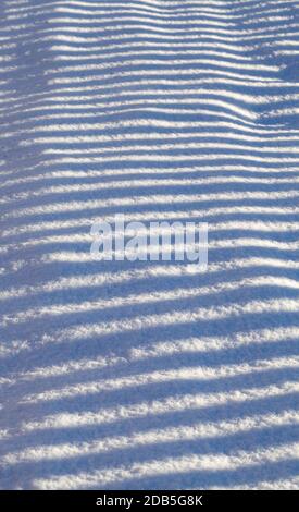striped shadows on the white snow from the fence, winter time, details on a Sunny day Stock Photo