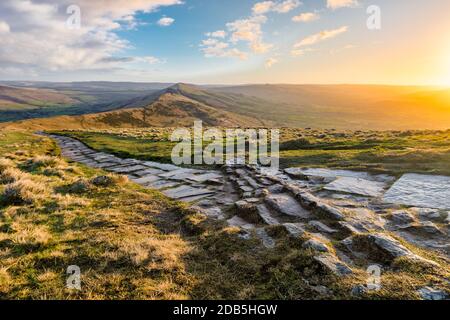 Rural stone footpath on the edge of Mam Tor in the Peak District at sunrise. Stock Photo