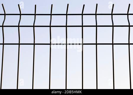 thin metal lattice decorative fence private area, but helps to protect the territory, against the blue sky Stock Photo