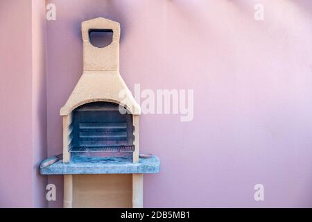 Traditional stone grill with pink wall in the background. Copy space. Stock Photo