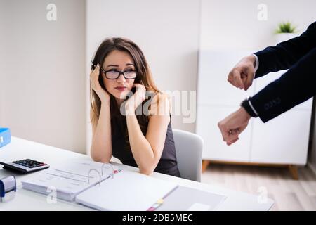 Angry Boss Pointing On Wrist Watch While Colleague Checking Invoice Stock Photo