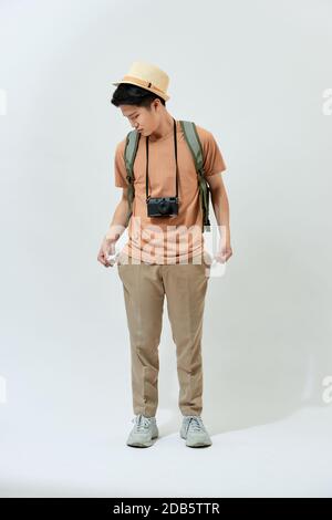 Young Asian tourist man lost his money and feel disappointed while standing over white background. Stock Photo