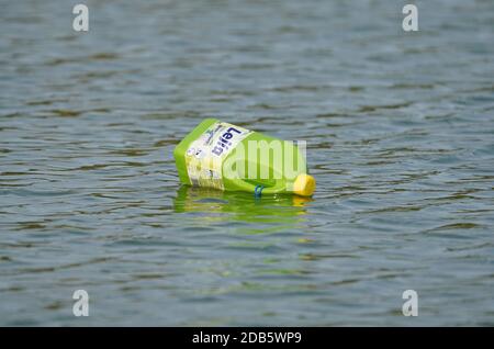 Plastic bottle of bleach floating in a river on water surface, pollution. Spain.