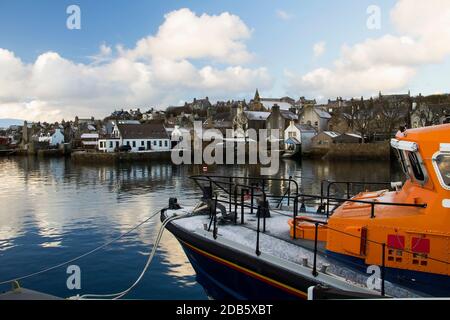Scottish town reflecting in water with lifeboat in foreground and traditional houses in background