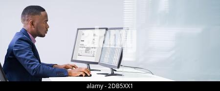 Side View Of A Businessman Checking Invoice On Computer At Workplace Stock Photo