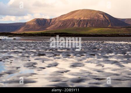 Closeup view of ripples on sandy beach in Scotland with big hill in the distance