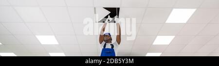 Young Male Electrician On Stepladder Installing Light On Ceiling Stock Photo
