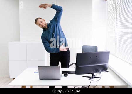 Young Businessman Doing Stretching Exercise In Office Stock Photo