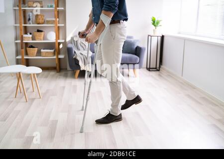 Disabled Man Using Crutches To Walk At Home Stock Photo