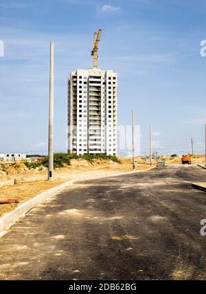 construction cranes on the site of construction of a new residential area, construction of a modern multi-storey building, a new asphalt road was buil Stock Photo