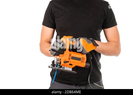 A man holds electric jigsaw in his hands, white background.