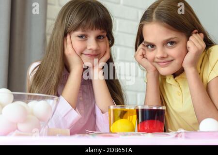 Two girls are waiting for the eggs to be painted in different colors for the Easter holiday. Stock Photo