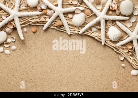 White starfishes, stones and seashells on sand background with fishing net. View from above. Flat lay Stock Photo
