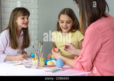 Mom with two daughters paint eggs for Easter Stock Photo