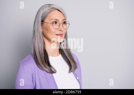 Portrait photo of confident concentrated experienced elder businesswoman wearing eyeglasses and purple cardigan isolated on grey color background Stock Photo