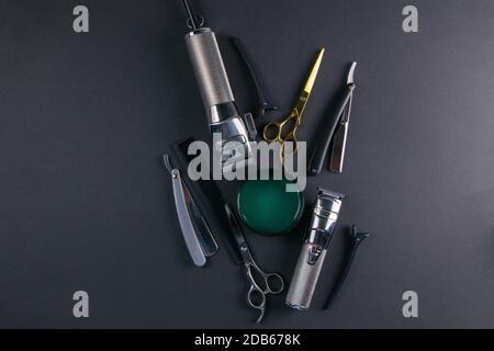 Scissors, hair clipper, combs, dangerous razor, gel for haircuts on black background. Hairdressing concept. Stock Photo