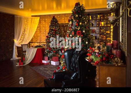 Christmas interior of the dark living room of the house. Christmas tree, lights of garlands on the walls, library Cabinet, books on the shelves. Luxur Stock Photo