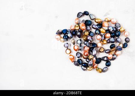 tangled hand crafted necklace from various river pearls on gray concrete background with copyspace Stock Photo