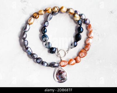 hand crafted necklace from colored river pearls with pendant on gray concrete background Stock Photo
