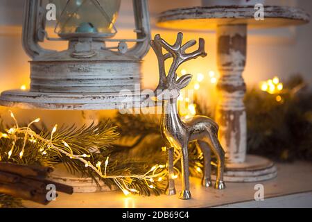 Christmas Decoration silver figure of a deer with branching horns, cinnamon sticks in festive lights garland yellow. New year, Christmas tree branch, Stock Photo