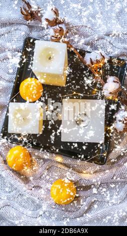 Flatlay Inspiration winter cozy still life composition with cotton, tangerines, candles and snowflakes on cozy gray plaid. Christmas card layout decoration idea. Flat lay, top view, copy space Stock Photo