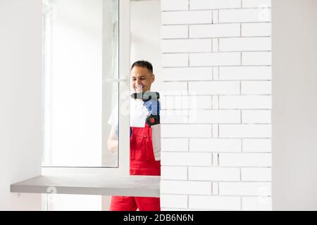 master with a screwdriver sets fittings on the window Stock Photo