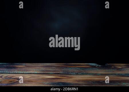 empty wooden table and black wall for product display with space for text or photo Stock Photo