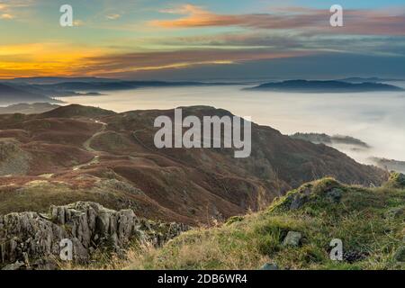 Beautiful Autumn sunrise from Loughrigg Fell in the Lake District with lovely lingering fog over the Cumbrian Valley. Stock Photo