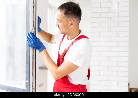 master with a screwdriver sets fittings on the window Stock Photo