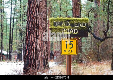 A dead end road sign on a snowy lane in a ponderosa pine forest along the Metolius River in the Cascade Range of central Oregon. The community is Camp Stock Photo