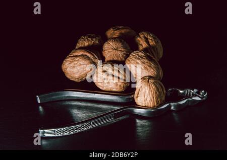 Walnuts with nutcracker over black background. Stock Photo