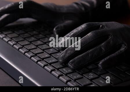 cybercriminal hands in gloves on laptop keyboard Stock Photo