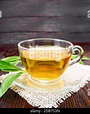 Herbal tea with sage in a glass cup on burlap on wooden board background Stock Photo