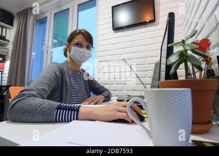 A sick quarantined girl in self-isolation at home works remotely in a computer Stock Photo