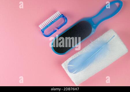 The concept of beautiful and healthy feet. Pedicure brush, foot stone and white towels with blue pen on a pink background. Top views with clear space. Stock Photo