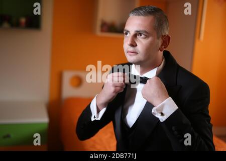 Close up of a man in a white shirt, black suit and a bow tie. Man's hands. Photo session of the groom. Wedding pictures. Businessman Stock Photo